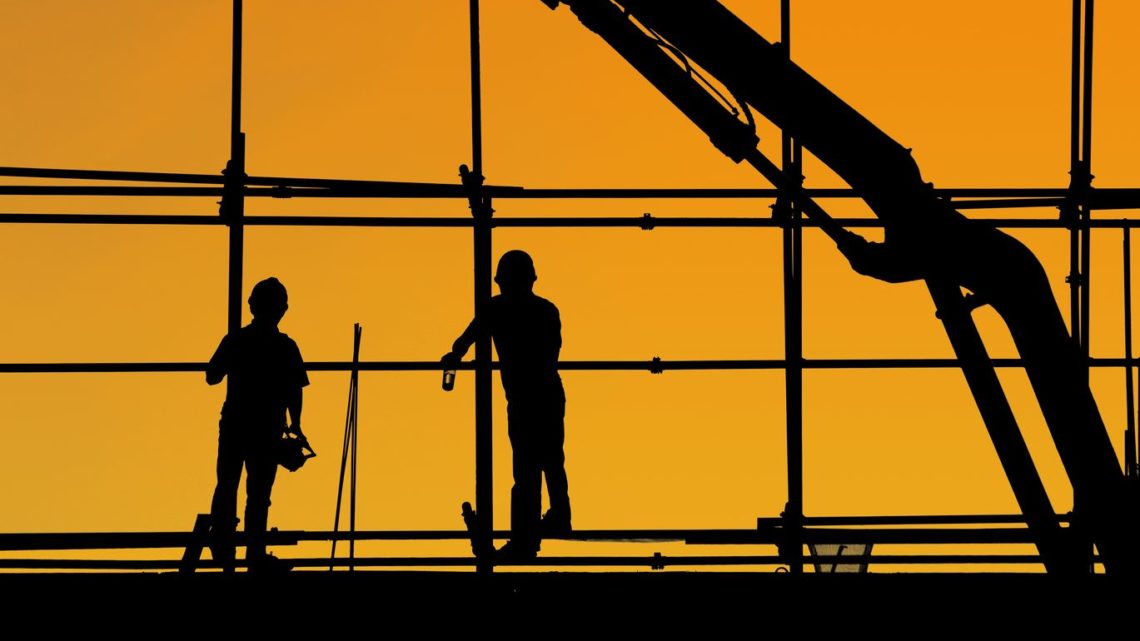 construction workers at twilight with crane in background