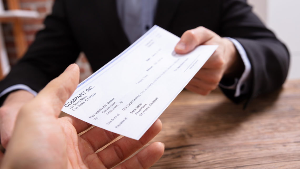 Man's Hands Giving Check To Other Person