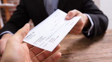 Man's Hands Giving Check To Other Person