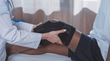 Cropped image of doctor putting knee brace on patient