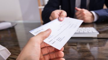 detail shot of one person handing a check to another person