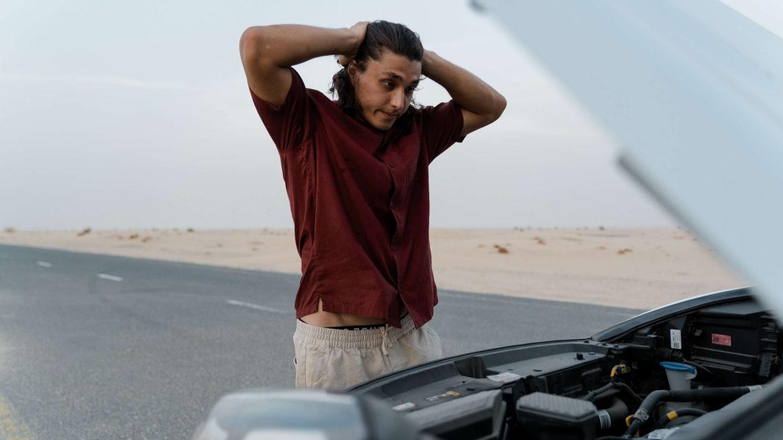 Man Looking at Defective Car in Frustration