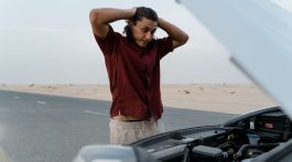 Man Looking at Defective Car in Frustration