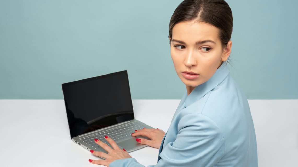 woman typing on her laptop anxiously looking over her shoulder