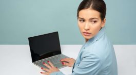 woman typing on her laptop anxiously looking over her shoulder