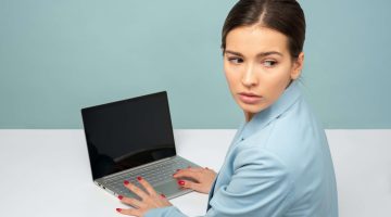 woman typing on her laptop anxiously looking over her shoulder