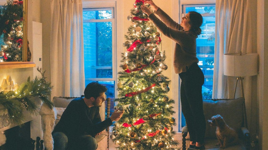 two individuals decorating a Christmas tree