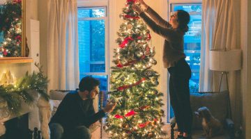 two individuals decorating a Christmas tree