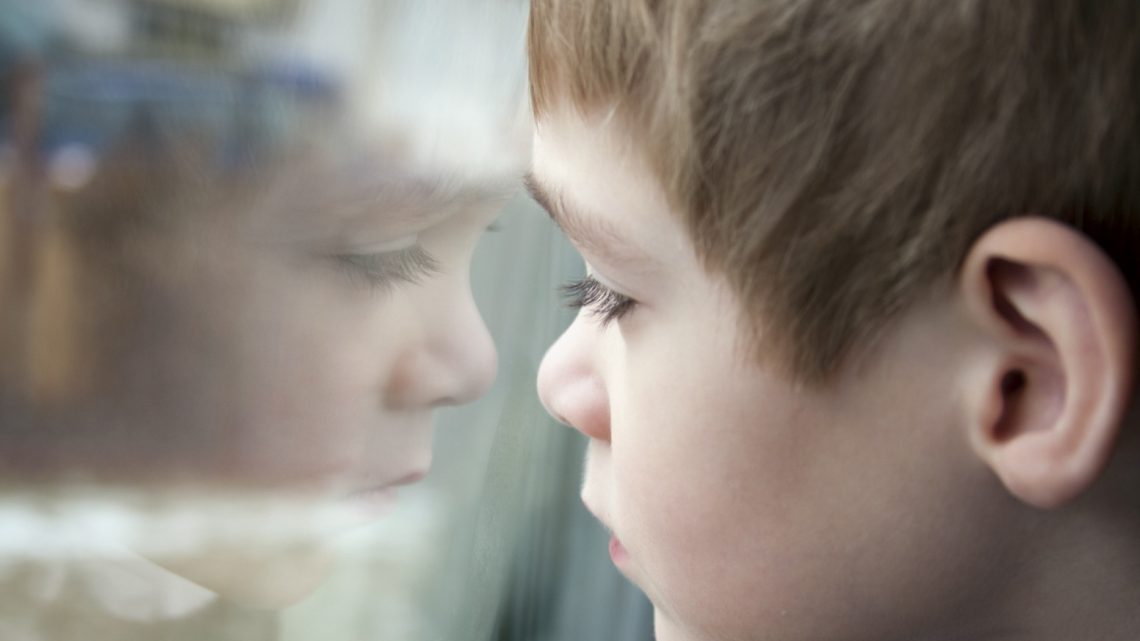 Young child sad looking at reflection.