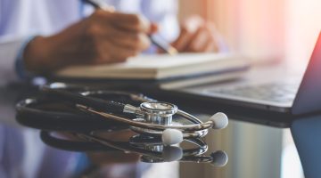 stethoscope on table with a doctor in the background
